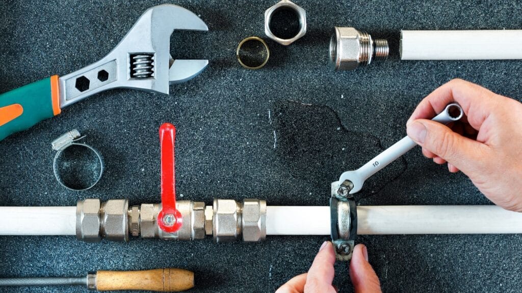 Plumber repairing a pipe valve with an adjustable wrench in Greenacres