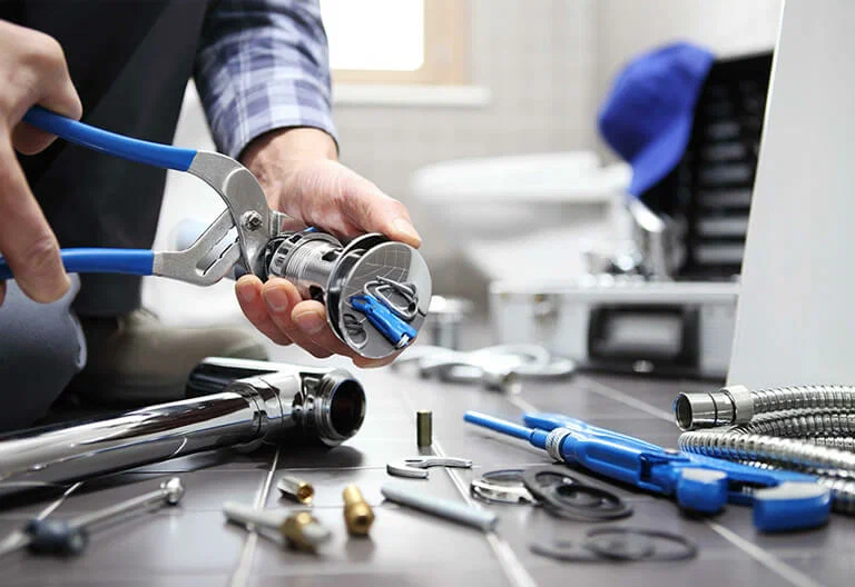 Technician repairing a plumbing fixture with professional tools in Greenacres