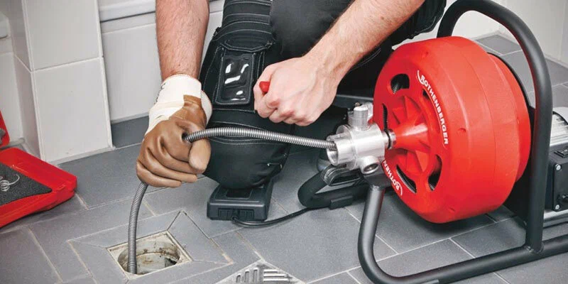 Plumber using a drain-cleaning machine in Greenacres