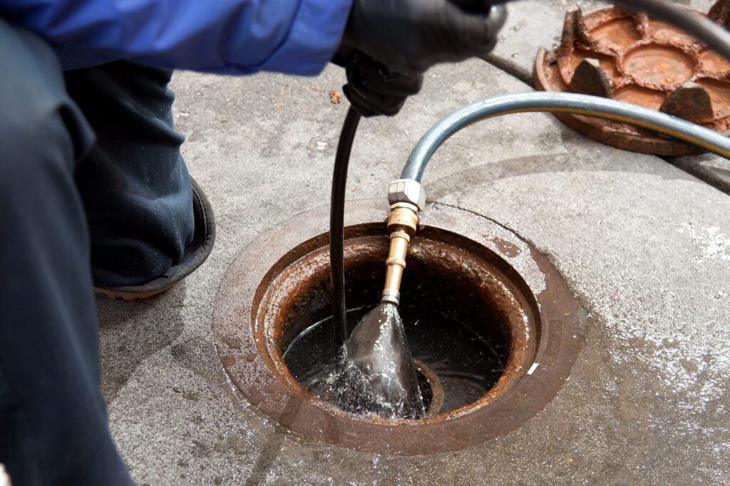 Plumber hydro jetting a sewer line through a manhole in Greenacres