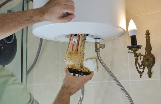 Technician removing mineral buildup from a water heater in Greenacres