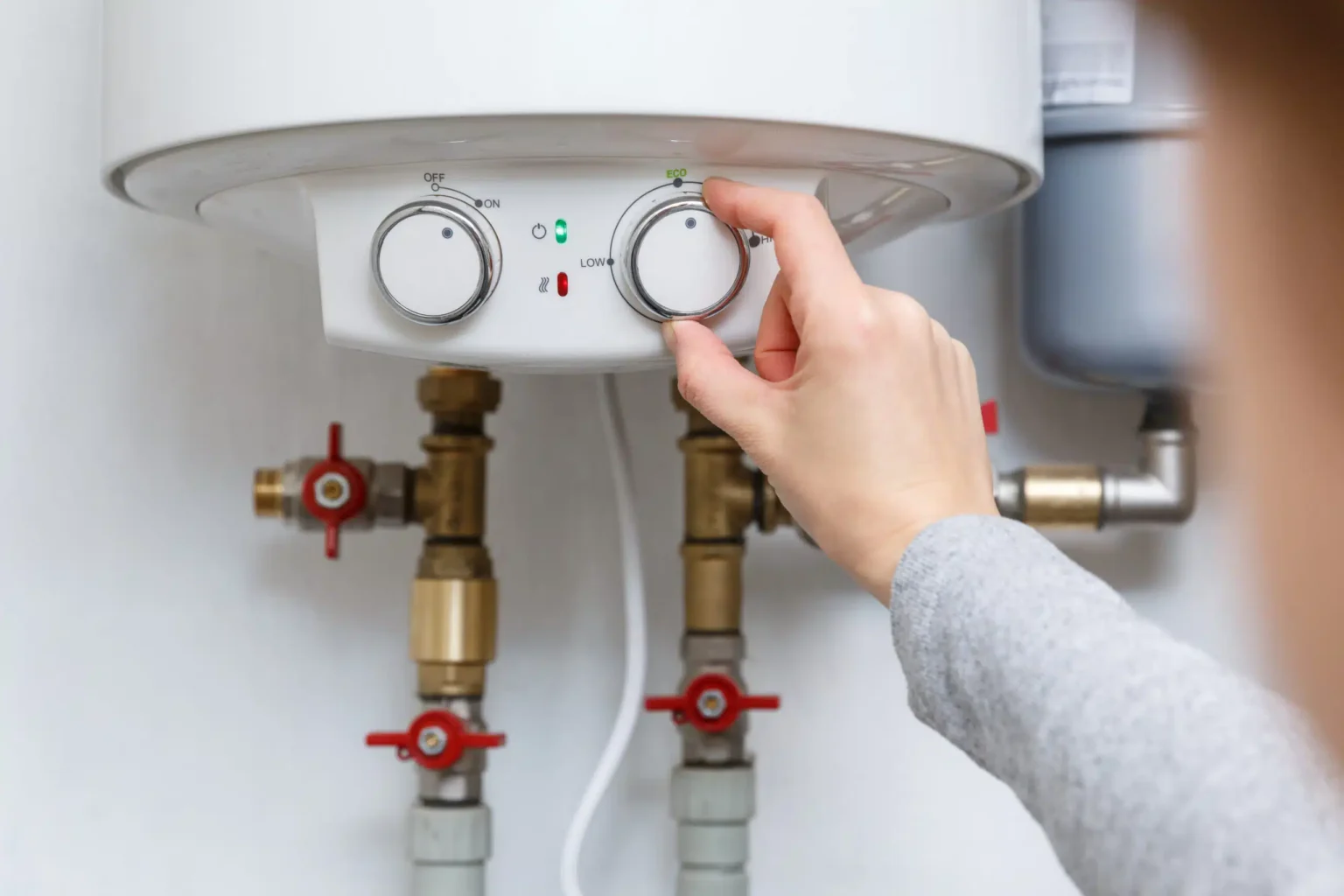Homeowner adjusting the temperature controls on a water heater in Greenacres